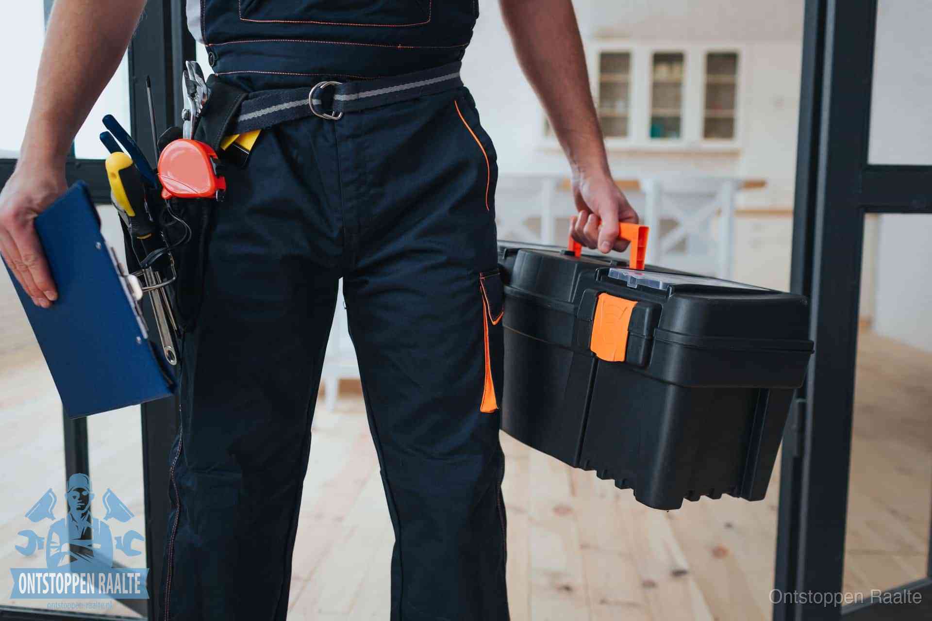 Een monteur met gereedschapsriem en klembord in een keuken, klaar om een transparante prijs voor het gootsteen ontstoppen in Raalte te geven