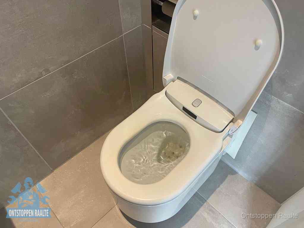 Een toiletpot vol troebel water met drijvend papier en restanten, de meest voorkomende oorzaak van een verstopte wc in Raalte