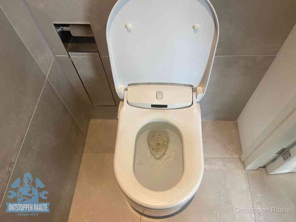 Een wit hangtoilet waarin een prop wc-papier op het water blijft drijven, een duidelijk signaal van een verstopte wc in Raalte
