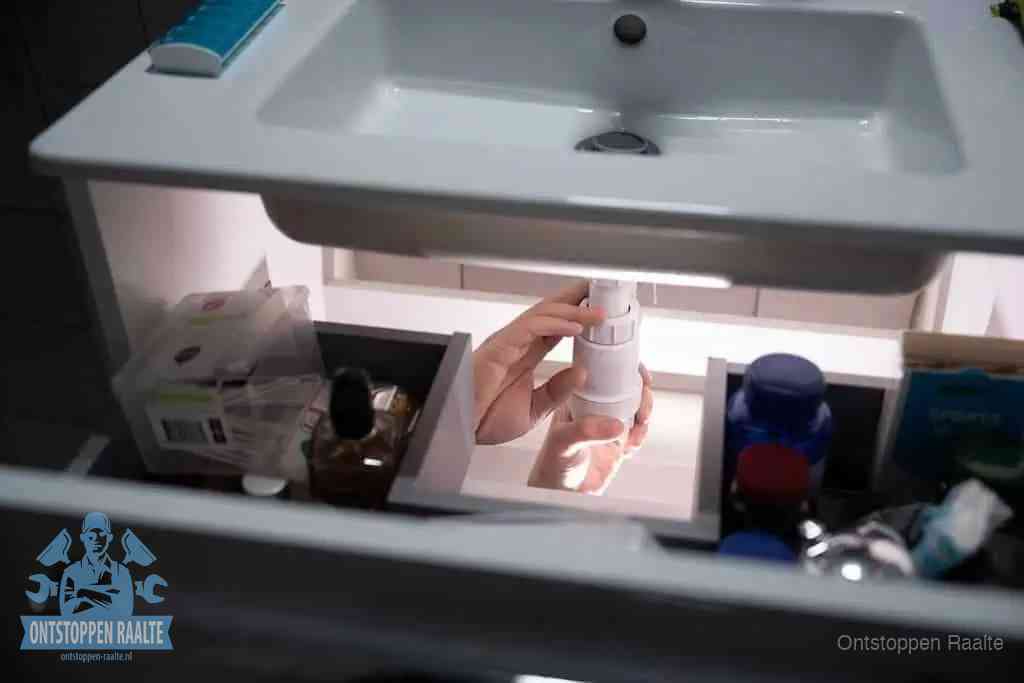 Een pompfles met zeep boven een wastafel in de toiletruimte, de warm water en afwasmiddel-methode om de wc te ontstoppen in Raalte