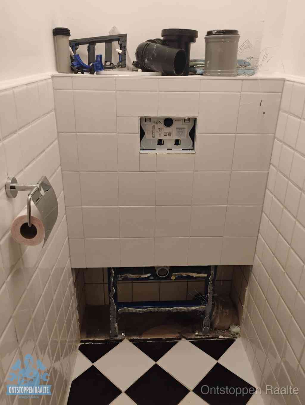 Een toiletruimte waar het hangtoilet en de inbouwreservoir-onderdelen zijn vrijgelegd voor onderhoud, periodiek nazicht voorkomt een wc-verstopping in Raalte